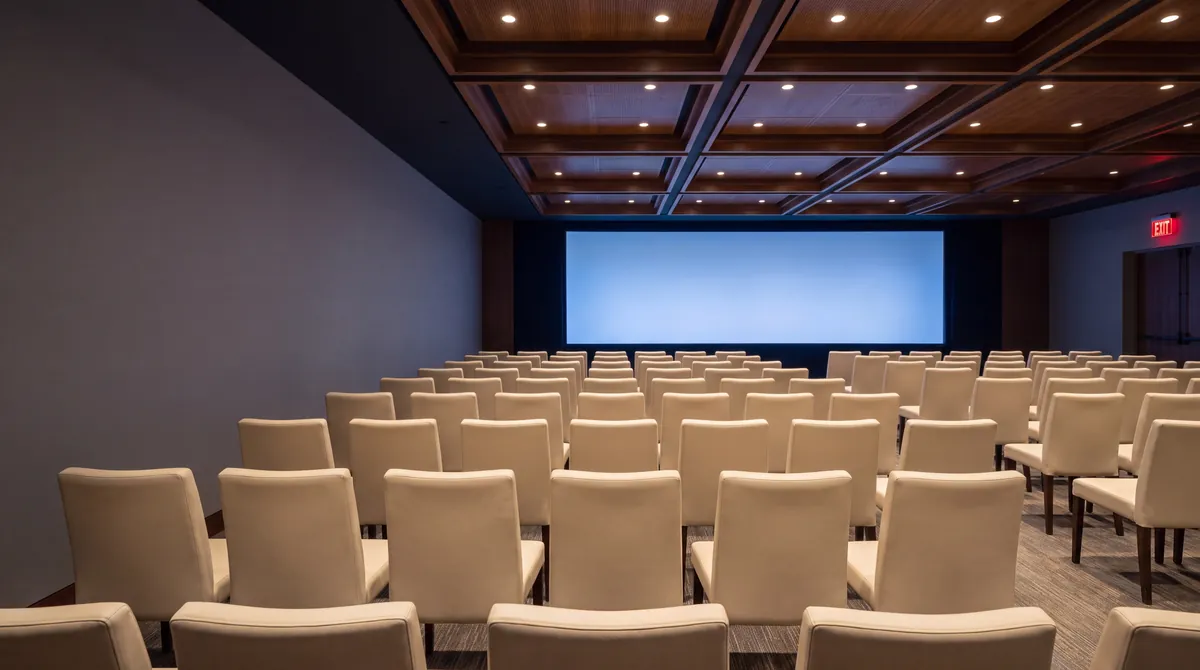 A conference hall set with rows of cream chairs before a screen
