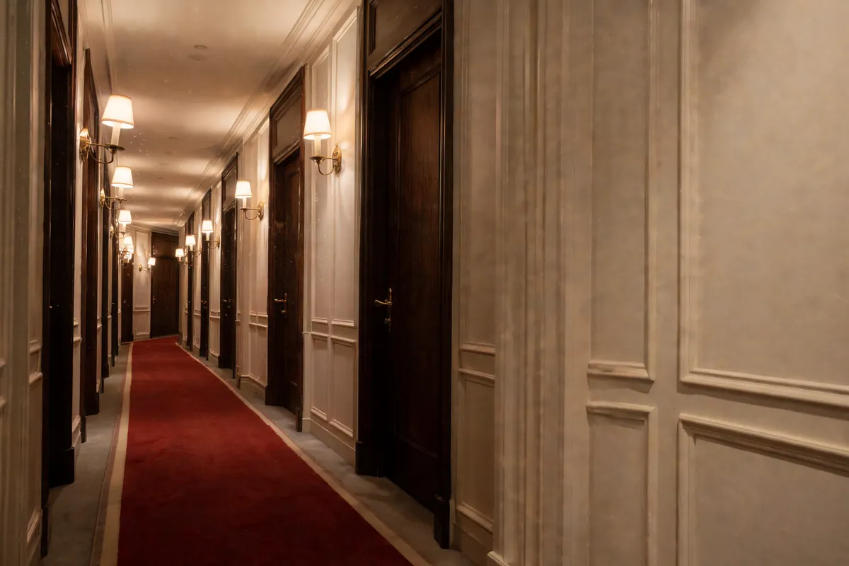 Hotel corridor with one suite door ajar and warm light spilling out